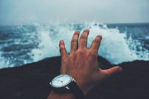時計をした手と海