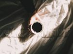 ベッドの上で目覚めのコーヒーを飲む人のが画像