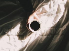 ベッドの上で目覚めのコーヒーを飲む人のが画像